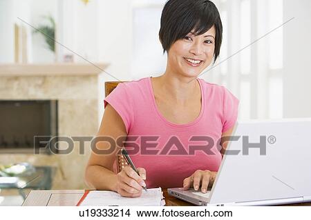Woman in dining room with laptop smiling View Large Photo Image Picture - Woman in dining room with laptop smiling. Fotosearch