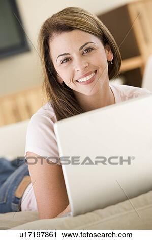 Woman in living room using laptop smiling View Large Photo Image Stock Image - Woman in living room using laptop smiling. Fotosearch