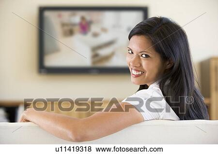 Woman in living room watching television smiling View Large Photo Image Stock Photo - Woman in living room watching television smiling. Fotosearch