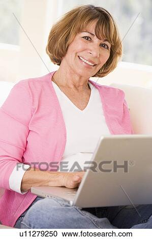 Woman in living room with laptop smiling View Large Photo Image Stock Image - Woman in living room with laptop smiling. Fotosearch