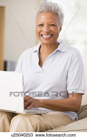 Woman in living room with laptop smiling View Large Photo Image Stock Image - Woman in living room with laptop smiling. Fotosearch
