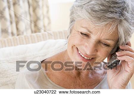 Stock Image - Woman indoors using cellular phone. Fotosearch