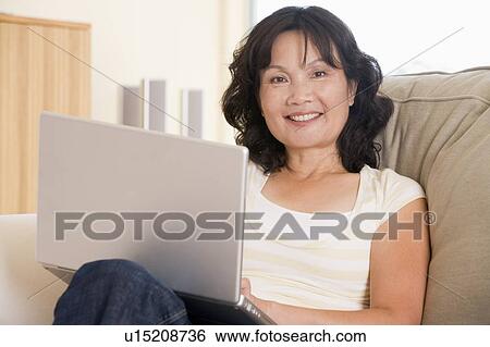 Woman sitting in living room smiling View Large Photo Image Stock Photograph - Woman sitting in living room smiling. Fotosearch