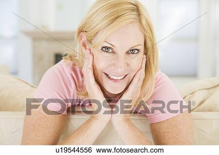 Woman sitting in living room smiling View Large Photo Image Stock Photograph - Woman sitting in living room smiling. Fotosearch