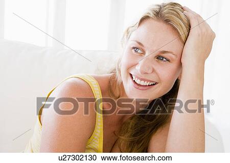 Stock Image - Woman sitting in living room. Fotosearch