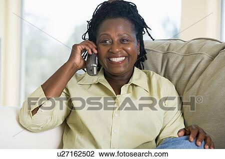 Woman sitting in living room using telephone and smiling View Large Photo Image Stock Image - Woman sitting in living room using telephone and smiling. Fotosearch