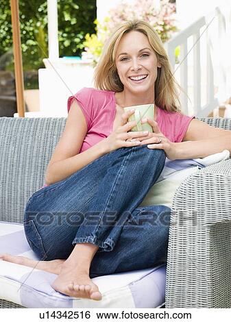 Woman sitting outdoors on patio with coffee smiling View Large Photo Image Stock Photograph - Woman sitting outdoors on patio with coffee smiling. Fotosearch