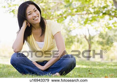 Woman sitting outdoors smiling View Large Photo Image Stock Photo - Woman sitting outdoors smiling. Fotosearch