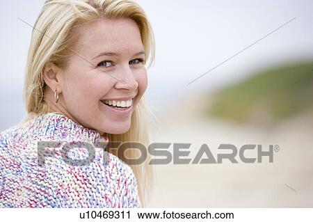 Stock Image - Woman standing at beach smiling. Fotosearch
