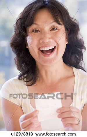 Stock Image - Woman with winning lottery ticket excited and smiling. Fotosearch