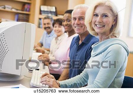 Stock Image - Five people at computer terminals in library (depth of field). Fotosearch