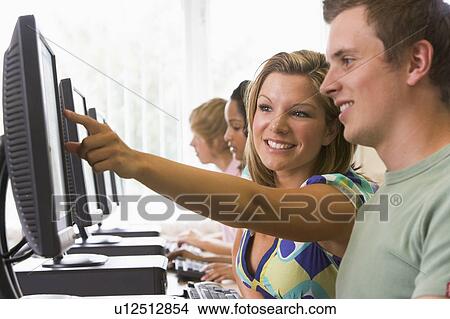 Picture - Four people sitting at computer terminals (depth of field/high key). Fotosearch