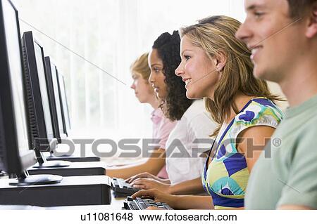 Stock Photo - Four people sitting at computer terminals (depth of field/high key). Fotosearch