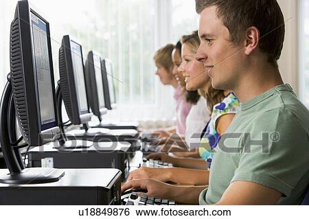 Stock Photograph - Four people sitting at computer terminals (depth of field/high key). Fotosearch
