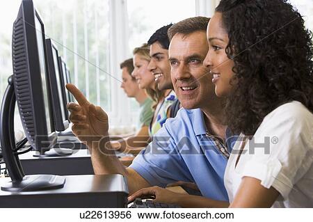 Four students sitting at computer terminals with teacher helping one of them (depth of field/high key) View Large Photo Image Stock Photograph - Four students sitting at computer terminals with teacher helping one of them (depth of field/high key). Fotosearch