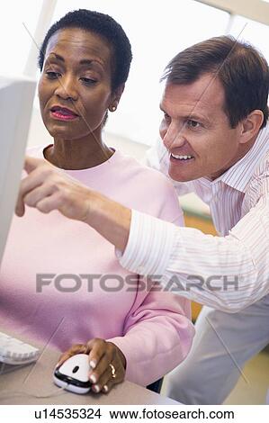 Picture - Man and woman at computer smiling and pointing at monitor (high key). Fotosearch