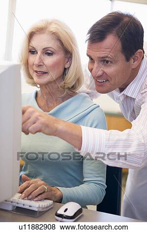 Man and woman at computer typing and pointing (high key) View Large Photo Image Stock Photo - Man and woman at computer typing and pointing (high key). Fotosearch
