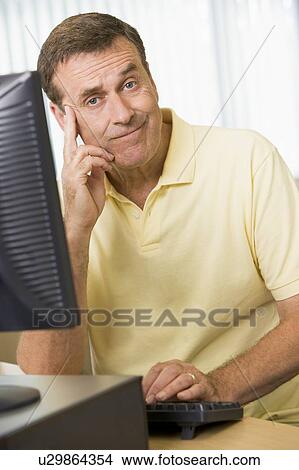 Picture - Man sitting at a computer terminal bored (high key). Fotosearch