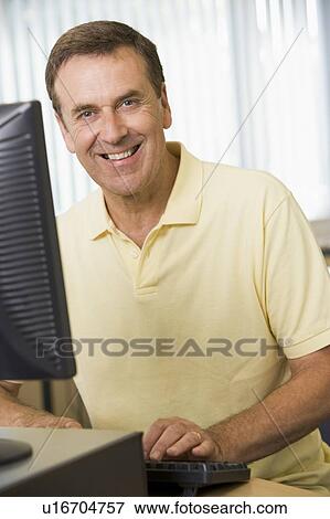 Man sitting at a computer terminal typing (high key) View Large Photo Image Stock Photo - Man sitting at a computer terminal typing (high key). Fotosearch