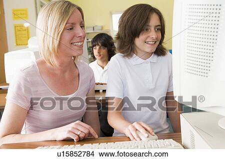 Student and teacher at computer terminal with student in background View Large Photo Image Picture - Student and teacher at computer terminal with student in background. Fotosearch