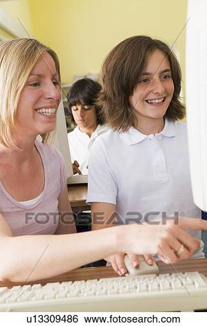 Student and teacher at computer terminal with student in background (selective focus) View Large Photo Image Stock Photograph - Student and teacher at computer terminal with student in background (selective focus). Fotosearch