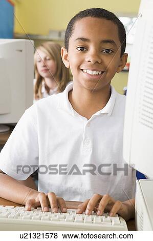 Student at computer terminal typing with student in background (selective focus) View Large Photo Image Stock Photo - Student at computer terminal typing with student in background (selective focus). Fotosearch