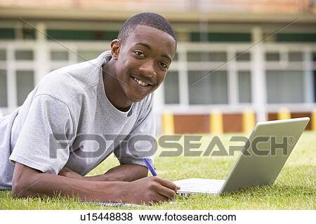 Student lying outdoors on lawn with laptop View Large Photo Image Stock Photo - Student lying outdoors on lawn with laptop. Fotosearch