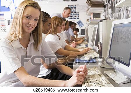 Stock Photography - Students working on computer workstations with teacher. Fotosearch