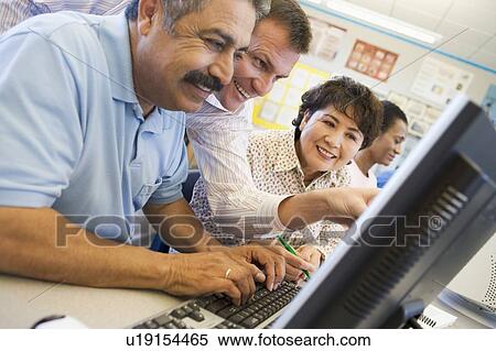 Teacher helping adult students at computer terminals View Large Photo Image Stock Photography - Teacher helping adult students at computer terminals. Fotosearch