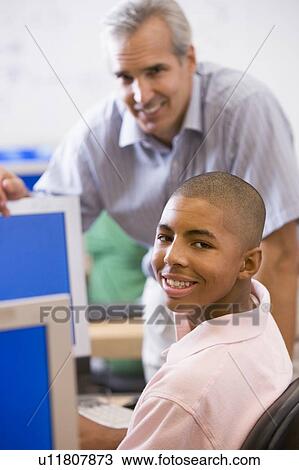 Teacher with male student in computer class View Large Photo Image Stock Image - Teacher with male student in computer class. Fotosearch