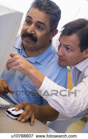 Stock Photo - Two men at computer pointing at monitor (high key). Fotosearch