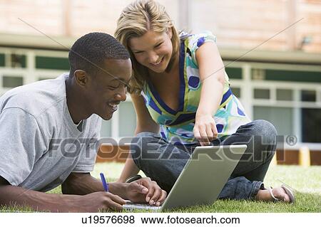 Two students outdoors on lawn with laptop View Large Photo Image Stock Photo - Two students outdoors on lawn with laptop. Fotosearch