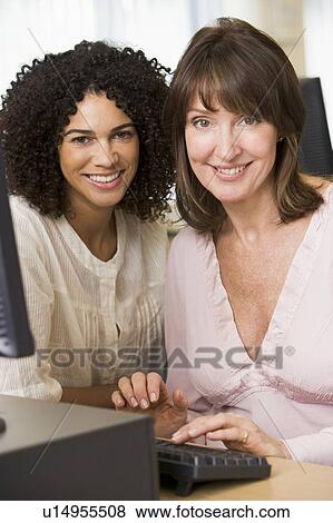 Two women at a computer terminal typing (high key) View Large Photo Image Stock Photo - Two women at a computer terminal typing (high key). Fotosearch