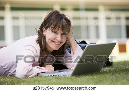 Woman lying on lawn of school with laptop View Large Photo Image Stock Photography - Woman lying on lawn of school with laptop. Fotosearch