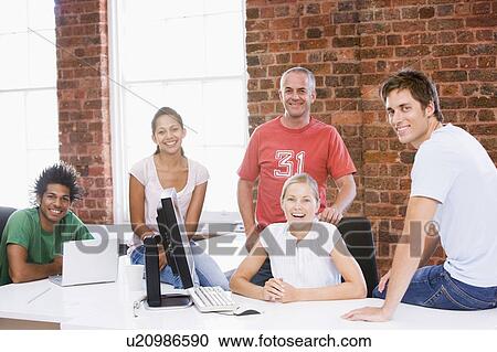 Stock Image - Five businesspeople in office space smiling. Fotosearch