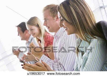 Four businesspeople applauding indoors smiling View Large Photo Image Stock Photo - Four businesspeople applauding indoors smiling. Fotosearch
