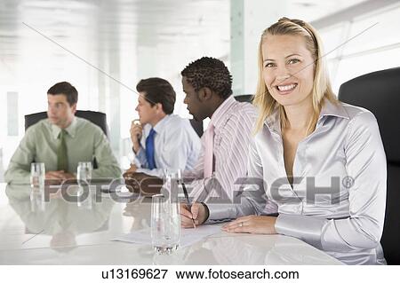Stock Photo - Four businesspeople in a boardroom smiling. Fotosearch