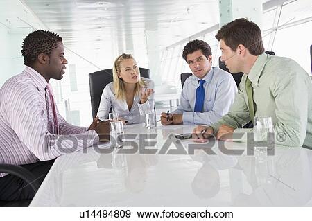Stock Photo - Four businesspeople in a boardroom talking. Fotosearch