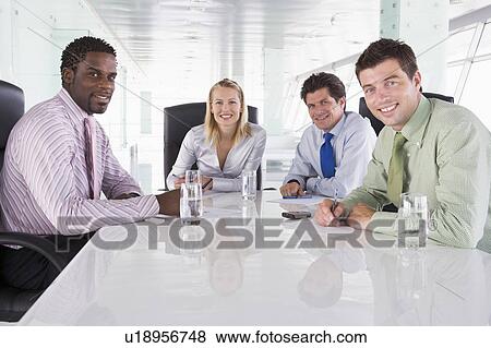 Stock Photo - Four businesspeople in a boardroom smiling. Fotosearch