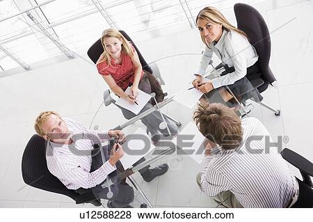Four businesspeople in boardroom with paperwork smiling View Large Photo Image Stock Photo - Four businesspeople in boardroom with paperwork smiling. Fotosearch