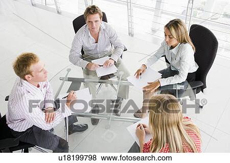 Four businesspeople in boardroom with paperwork View Large Photo Image Stock Photo - Four businesspeople in boardroom with paperwork. Fotosearch