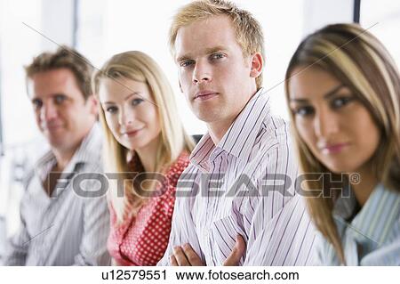 Stock Image - Four businesspeople sitting indoors smiling. Fotosearch