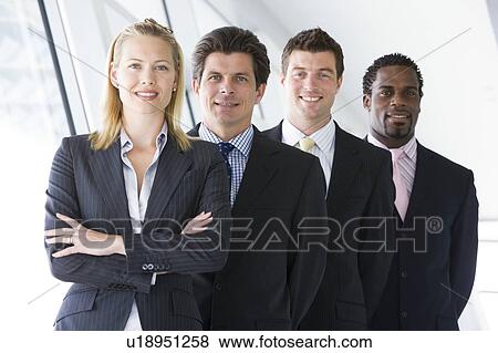 Stock Photo - Four businesspeople standing in corridor smiling. Fotosearch
