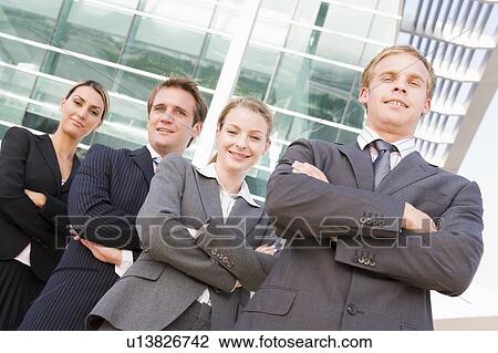Four businesspeople standing outdoors smiling View Large Photo Image Stock Image - Four businesspeople standing outdoors smiling. Fotosearch