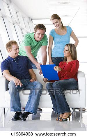 Four people in lobby pointing at clipboard smiling View Large Photo Image Stock Photo - Four people in lobby pointing at clipboard smiling. Fotosearch