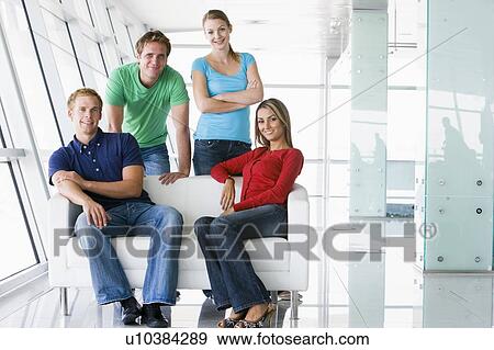 Stock Photo - Four people in lobby smiling. Fotosearch