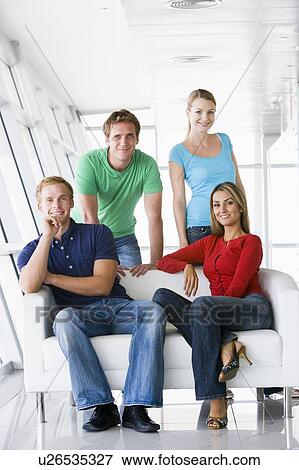 Stock Photo - Four people in lobby smiling. Fotosearch