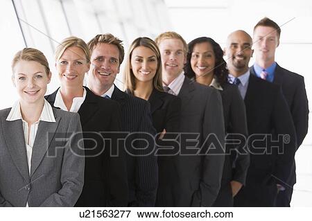 Group of co-workers standing in office space smiling (high key/depth of field) View Large Photo Image Stock Photo - Group of co-workers standing in office space smiling (high key/depth of field). Fotosearch