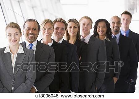 Group of co-workers standing in office space smiling (high key/depth of field) View Large Photo Image Stock Photograph - Group of co-workers standing in office space smiling (high key/depth of field). Fotosearch