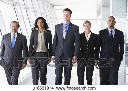 Picture - Group of co-workers walking in office space smiling (high key). Fotosearch